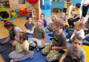 Dzieci siedzą na dywanie - Oliwia, Denisa, Ania, Hana, Miłosz, Iwo, Karol, Jasiu, Adaś oraz Kuba.